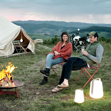 Camping scene with firepit, furniture, and portable lighting