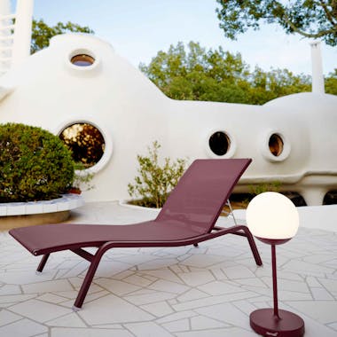 Burgundy sunlounger with outdoor lamp on patio
