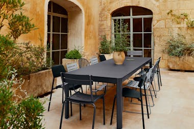 Large outdoor table with a mixture of chairs in blacks and greys