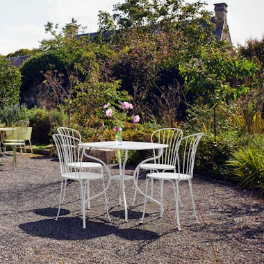  Outdoor table with four wire chairs in garden