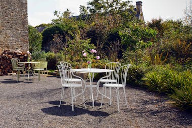  Outdoor table with four wire chairs in garden