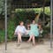 Two ladies sitting on a garden bench under a pergola