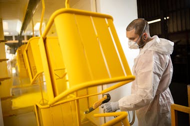 Worker applies paint to Fermob furniture
