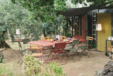 Metal folding outdoor dining table and chairs in a rustic setting