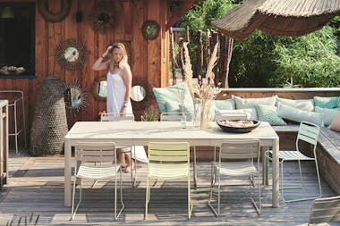 Woman stands behind Fermob extending outdoor dining table in Clay Grey colour