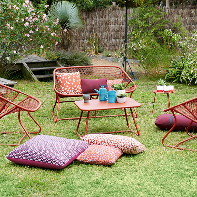 Fermob Sixties outdoor casual setting in Red Ochre on grass in a garden