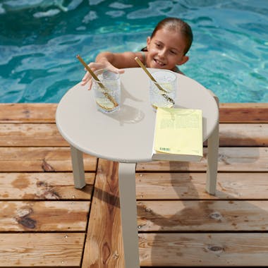 Child reaches from pool for drink off Alize side table in Clay Grey