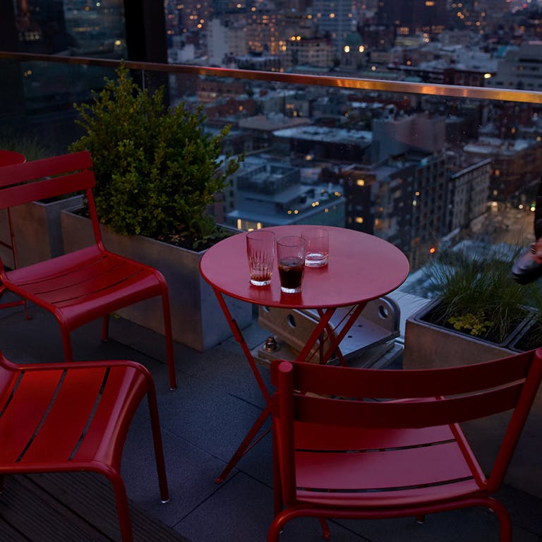 New York highrise restaurant at dusk with Fermob furniture in Poppy