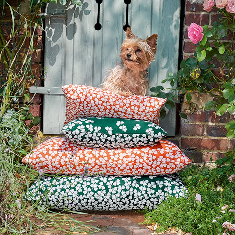 A stack of Fermob Trefle cushions with a small dog