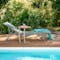 Fermob Alize XS Sunlounger in Cactus with offset side table in Nutmeg sits by pool
