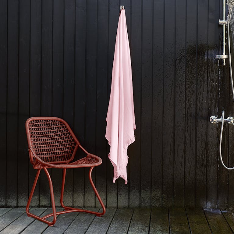 Fermob outdoor dining chair from the Sixties collection in Red Ochre in front of black wall