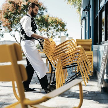 Man using trolley to move Luxembourg cafe chairs