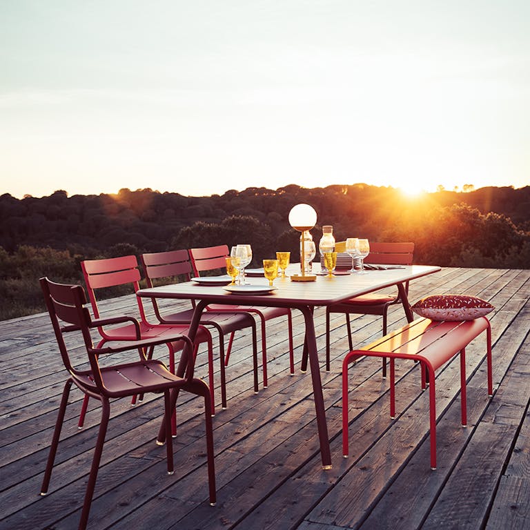 Fermob luxembourg dining table with benches and chairs at sunset