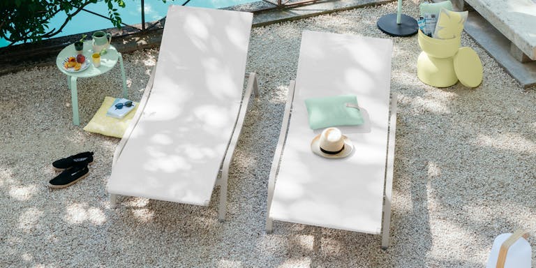 Man stands next to pool and two sun loungers