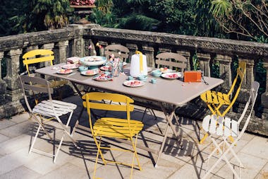 Fermob La Mome folding chairs and Caractere large folding outdoor table on a paved terrace