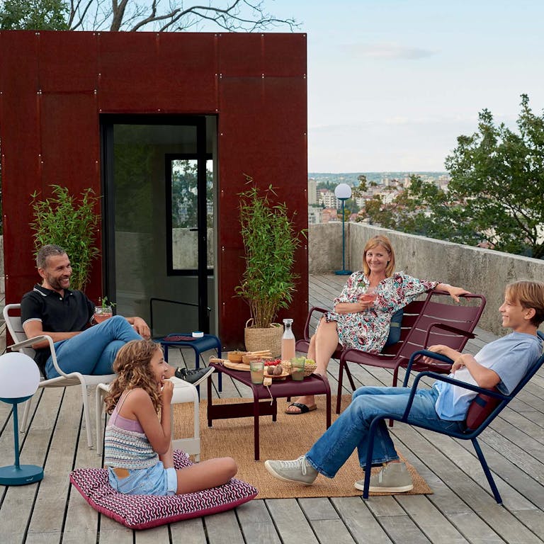 Family gathered together on roof terrace on Fermob Luxembourg outdoor furniture