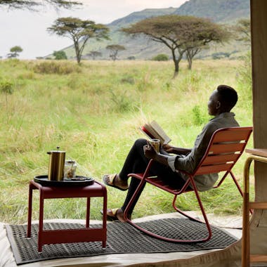 Man relaxing on Fermob chair outside tent at Angama Mara