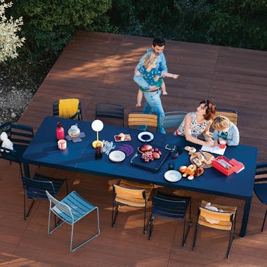 Long extendable outdoor table on a deck with family enjoying food