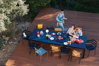 Long extendable outdoor table on a deck with family enjoying food