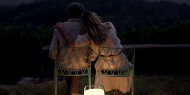 Couple sitting on Fermob Kintbury chairs with Balad outdoor lamp