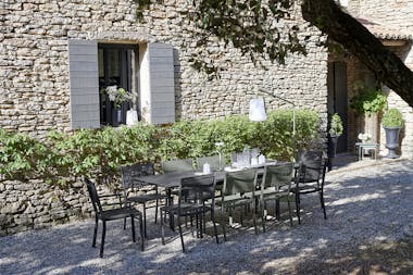 Fermob Costa Extending outdoor table and chairs in rustic French courtyard