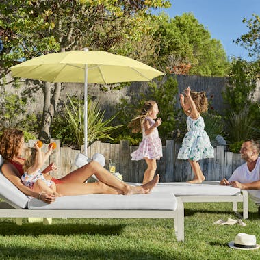 Family relaxing by the pool on Fermob Bellevie sunloungers