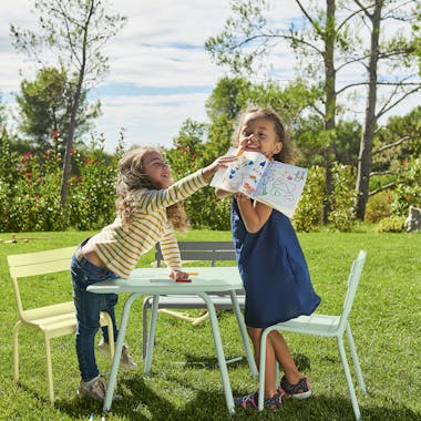 Children playing at Fermob Luxembourg Kid outdoor furniture in the garden.