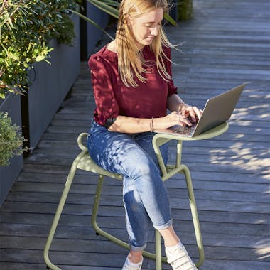Woman sitting side saddle and working at the Adadesk Rocking Desk outside