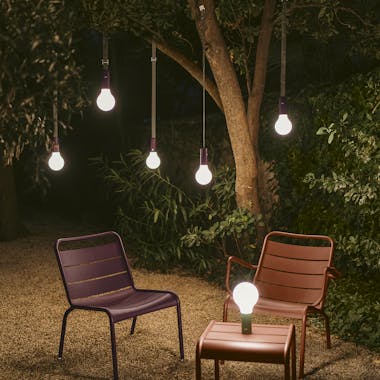 Fermob Aplo lamps suspended from tree in evening light